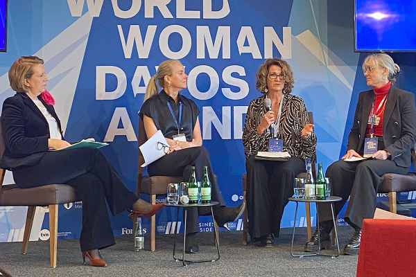 Four women sit on a stage in chairs for a panel discussion