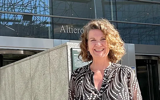 Woman stands outside a glass building