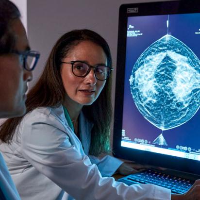 Personal sanitario revisando una radiografía en una pantalla en una sala en penumbra